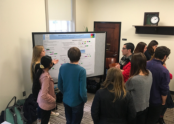 photo of students presenting research on Ditransitive constructions in Lulogooli. Daisy Mohiuddun, Joshua Morabito, Nicole Steiner. Photo also includes poster, students and faculty.