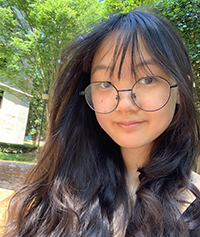 headshot of Valeria Li, peer mentor, is standing outside looking forward, greenery and trees in the background.